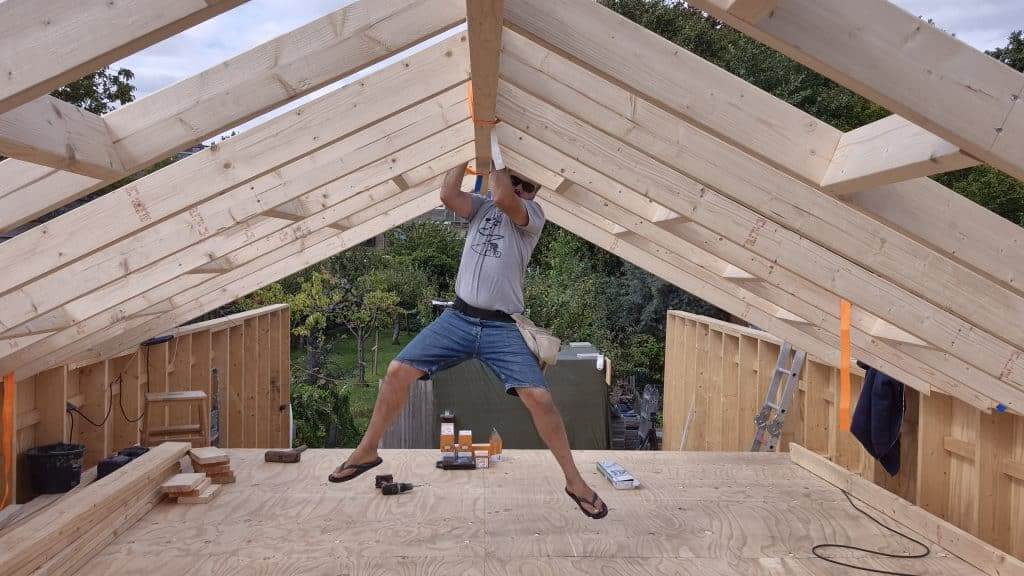 Martijn Plugge hangen aan een balk van het nieuwe tuinhuis